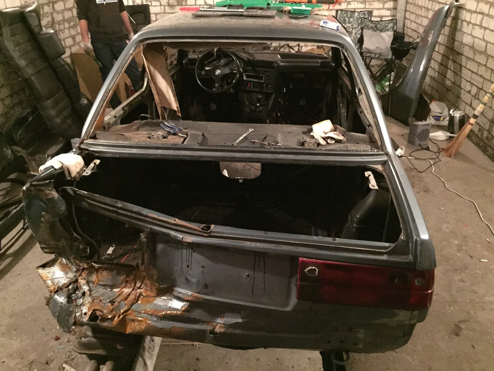 Rusted and damaged rear section of the E30 shell in a garage