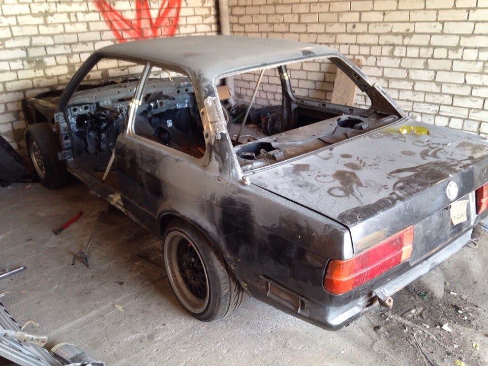 E30 stripped to a bare shell on stands in a garage