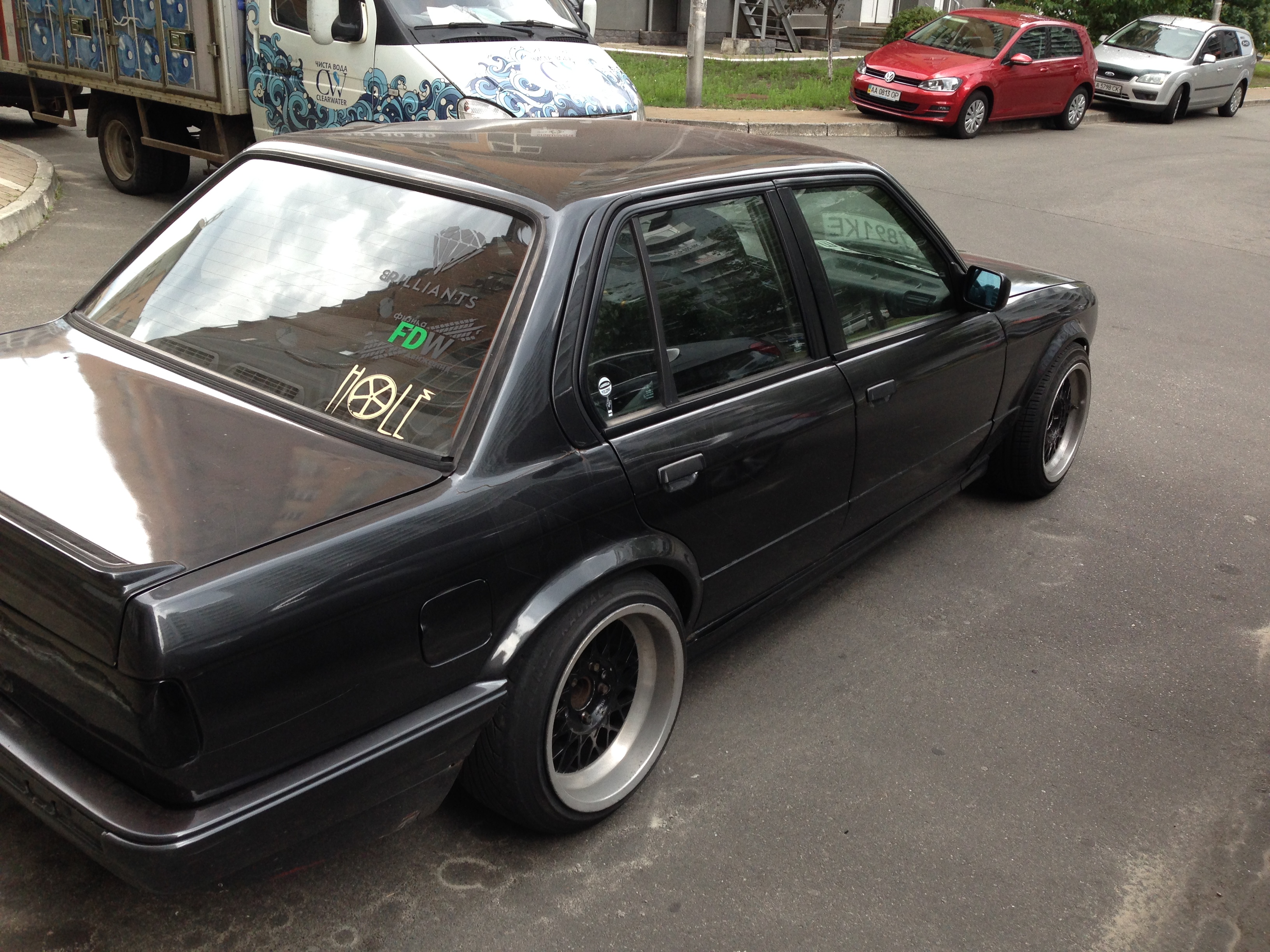 Black BMW E30 sedan side profile, lowered on staggered wheels